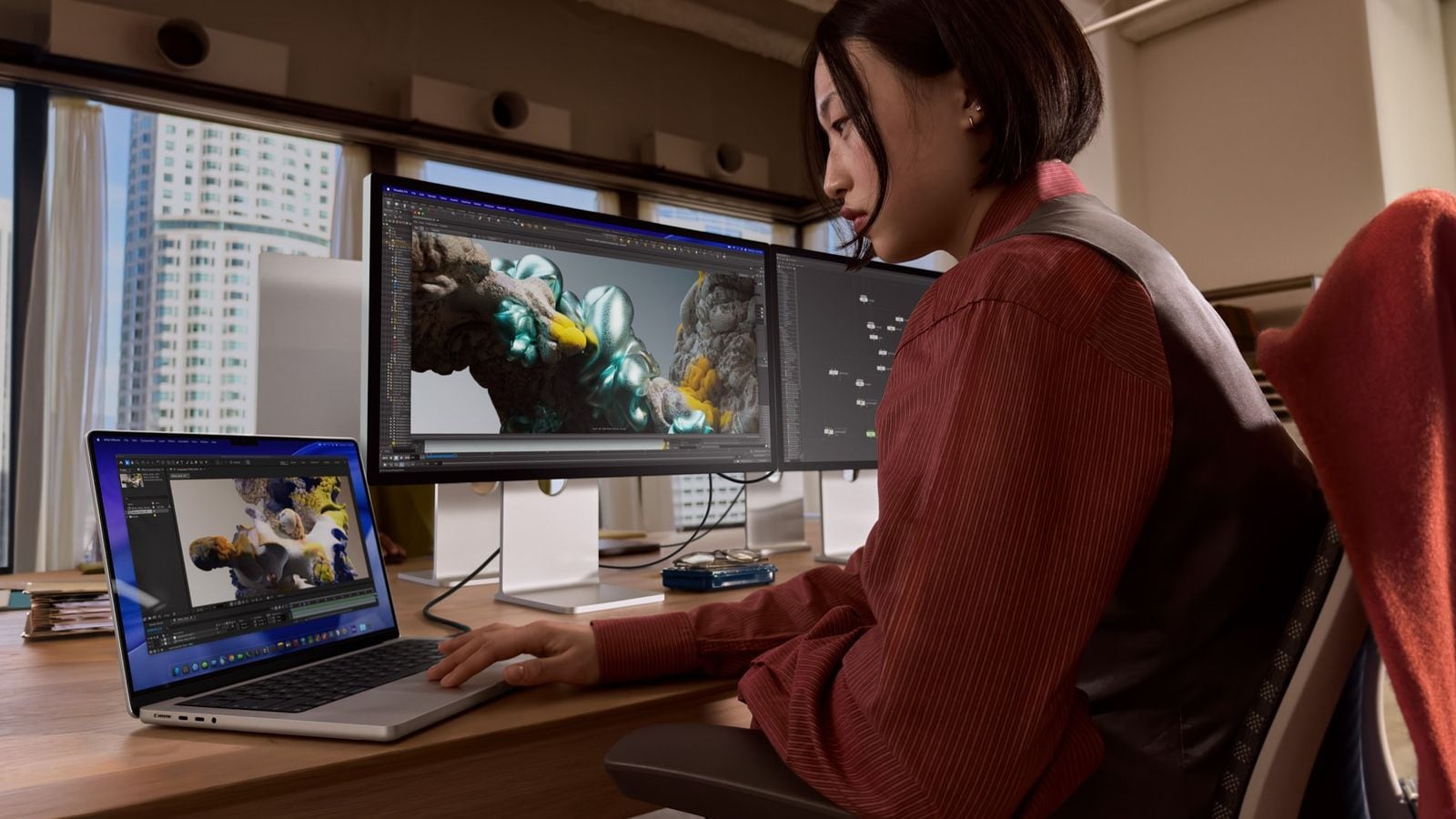 A MacBook Pro user works at their desk with two external displays.